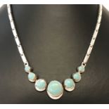 A silver & turquoise set necklace. Oblong silver links with graduating round cut turquoise pendants.