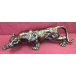 A bronzed cast metal figurine of a prowling panther.