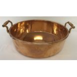 A Victorian copper 2 handled cooking pan with riveted decorative handles.