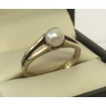 A 9ct vintage gold and pearl dress ring. A single pearl set in raised shoulders.
