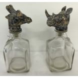 A pair of square shaped bottle decanters with animal head stoppers.