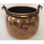 A very large antique copper cooking cauldron with riveted brass handle brackets and swing handle.