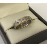 An 18ct white and yellow gold full eternity ring set with small diamonds, 3 stones missing.
