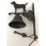 A wall hanging cast iron garden bell with dog detail.