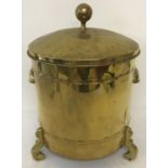 A vintage brass lidded coal bucket with scroll shaped feet and cup handles.