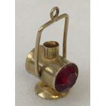 A 9ct gold lantern shaped charm, set with red coloured stone.