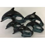 A collection of mid century Poole pottery dolphins with blue/green glaze.