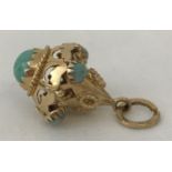 A 9ct gold decorative pendant style charm, set with round turquoise stones.