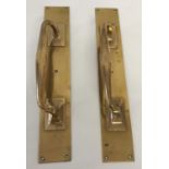 A pair of brass door handles mounted on finger plates.