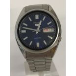 A men's Seiko 5 automatic wristwatch with blue face and see-through back case.
