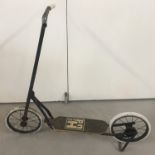 A vintage metal framed child's scooter with rubber wheels and metal stand.