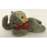 A Steiff laying down baby grey elephant. Red ribbon to neck and button to left ear.