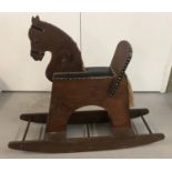 A vintage dark wood child's rocking horse with leather effect studded seat.