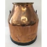 An antique copper milk churn with riveted handle brackets.