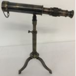 A small brass telescope mounted on an extending tripod base with folding feet.