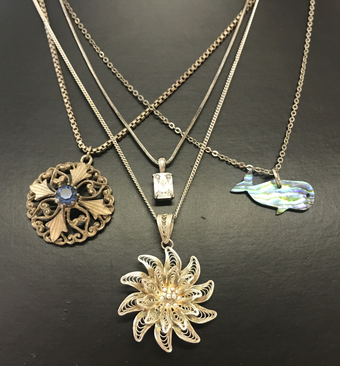 4 silver and white metal necklaces. A filigree flower pendant on a fine curb chain.