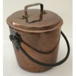 An antique copper straight sided, lidded cooking pot with riveted swing handle.