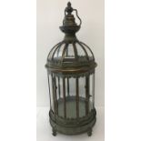 A large copper ornamental free standing lantern with glass panels and hanging hook.