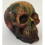 A large carved multi coloured resin, amber style skull figurine decorated with Pagan style symbols.