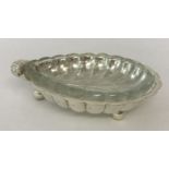 A silver plated shell shaped butter dish raised on tripod ball feet, complete with glass liner.