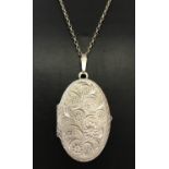 A large vintage oval silver locket with engraved floral detail to front.