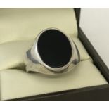 A men's silver signet ring set with an oval black onyx stone. Size T.