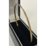A slim gold bangle with diamond cut decoration to outside rim. Tests as 9ct gold.