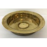 An antique brass large rimmed bowl with straight sides and domed central panel.