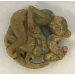 A carved Chinese jade roundel depicting figures in an erotic pose.