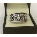 A men's silver band style ring with fleur de lis decoration. Size U½.