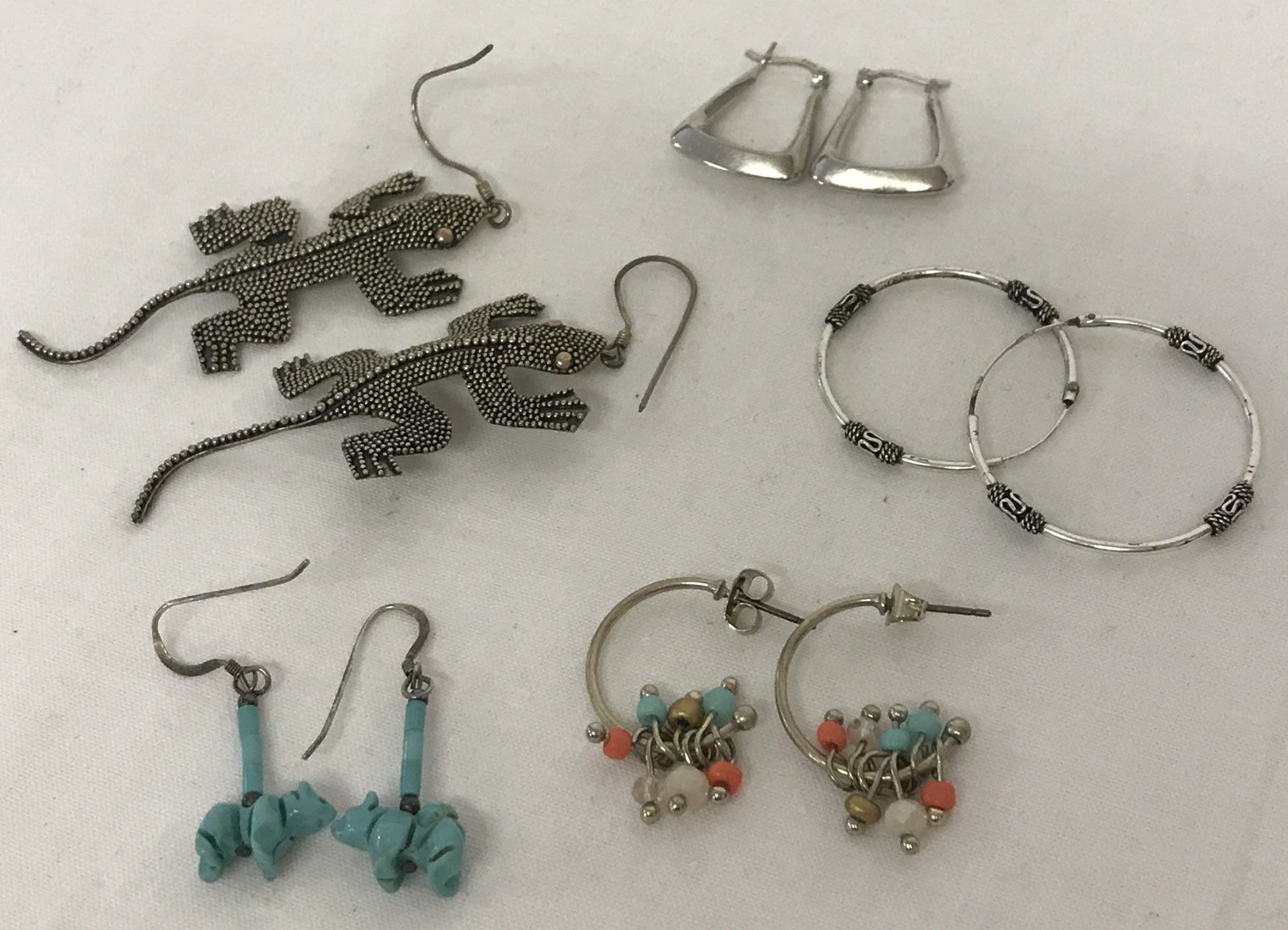 5 pairs of silver and white metal earrings in hoop and drop styles.