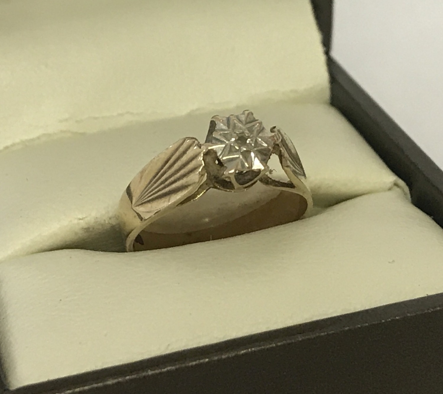 A vintage 9ct gold, illusion set diamond dress ring. Pattern to both shoulders.