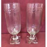 A pair of cut glass vases raised on pedestal stems with engraved detail and channelled design.