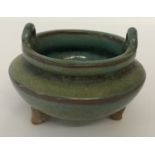 A Chinese porcelain censer with green speckled glaze, raised on tripod feet and with loop handles.