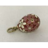An enamel and clear stone set, flower design egg charm/pendant with silver gilt fixing and bale.