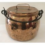 A very large, antique copper, lidded cooking cauldron with swing handle.