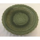 A large celadon glaze stoneware shallow bowl with floral and bird detail to inner bowl.