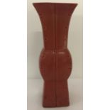 A square shaped Chinese ceramic vase with red glaze and channelled detail.