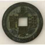 A large Chinese coin/token with central square shaped hole and Chinese symbols.