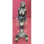 A large cast metal figurine of a mermaid in a seated position.