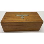 A WWII style wooden box with metal German eagle badge to lid.