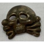 A German WWII style Allgemeine SS Totenkopf death head skull cap badge .