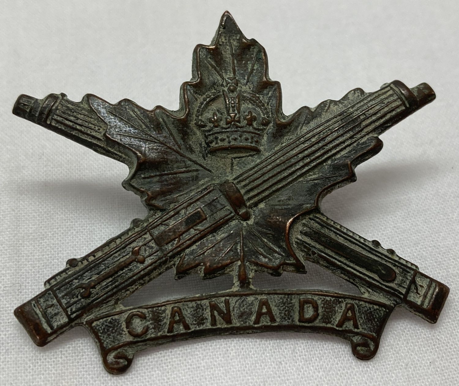 A WWI style Canadian Machine Gun Corps MGC cap badge.