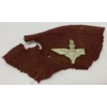 A WWII style plastic economy Parachute Regiment cap badge with broken wing on beret fragment.