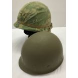 A Vietnam War style US M1 helmet with liner and mitch camo cover.