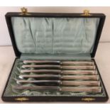 A cased set of 6 silver-plated butter knives, handles marked SS.