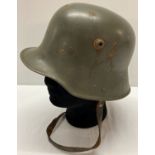 A WWI style Austrian M17 helmet with liner and chin strap.