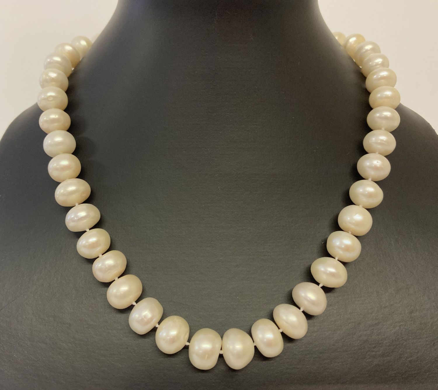 A 17" string of larger oval shaped cream freshwater pearls, with magnetic clasp.