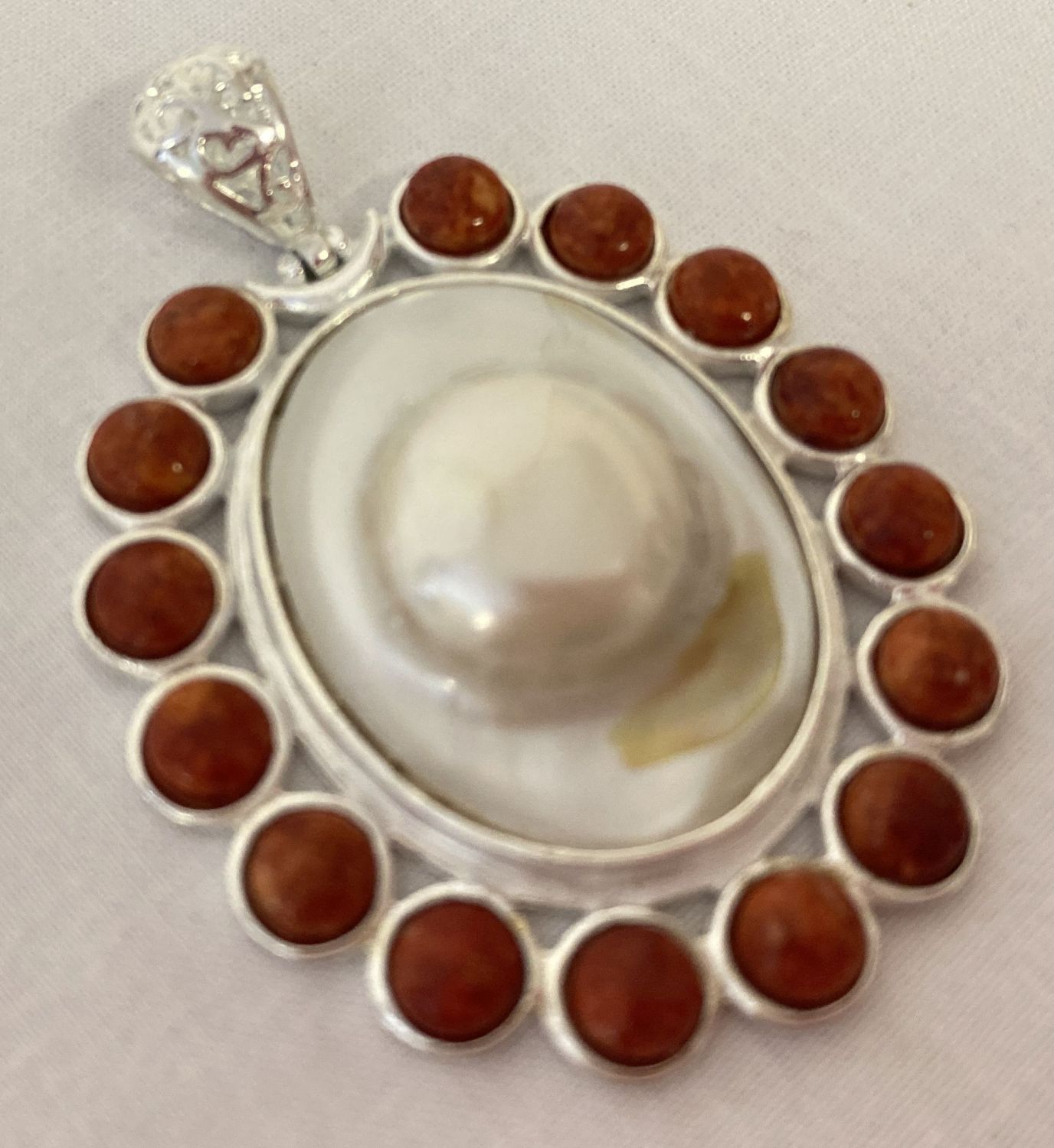 A large oval shaped coral and pearl pendant with pierced work bale.