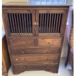 A dark wood 5 drawer, 2 door cabinet with slatted panel door fronts and brass handles.